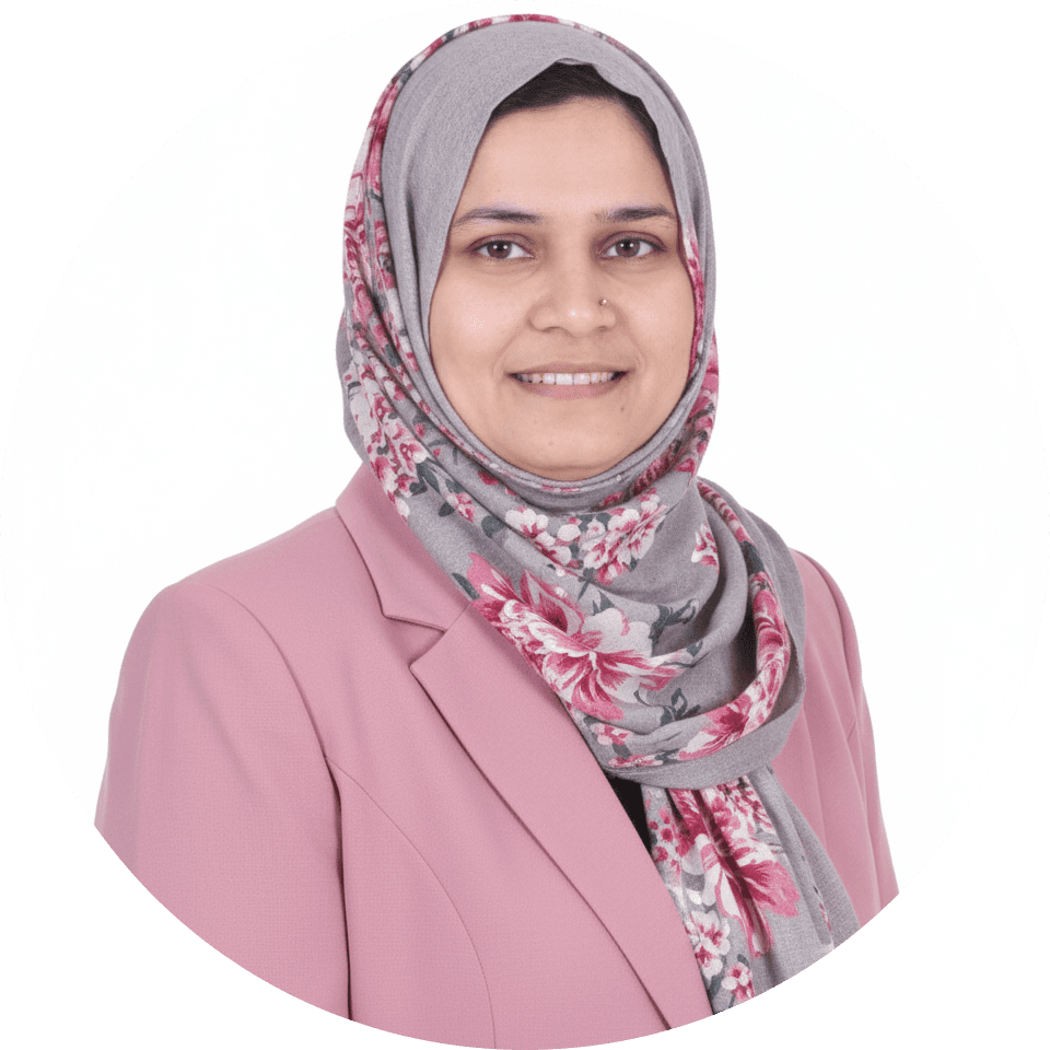 Smiling woman wearing a pink blazer and a grey floral hijab in a circular headshot.